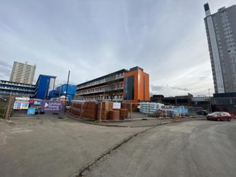 Building works fenced off and a low-rise block of flats with an orange facade