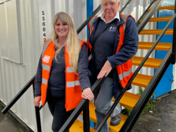 Two women in hi-vis jackets stand on stairs