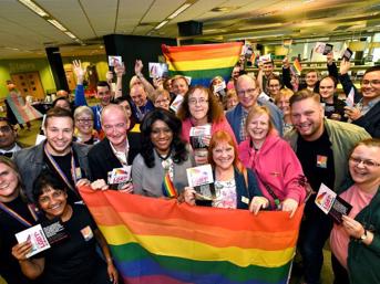 Group of people holding a rainbow flag at a Pride event