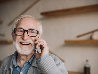 A man with glasses and a beard talks on the telephone