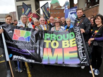 Group of people at a Pride event holding a banner