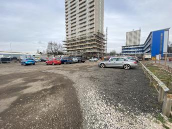 An unrefurbished block of flats and temporary car park