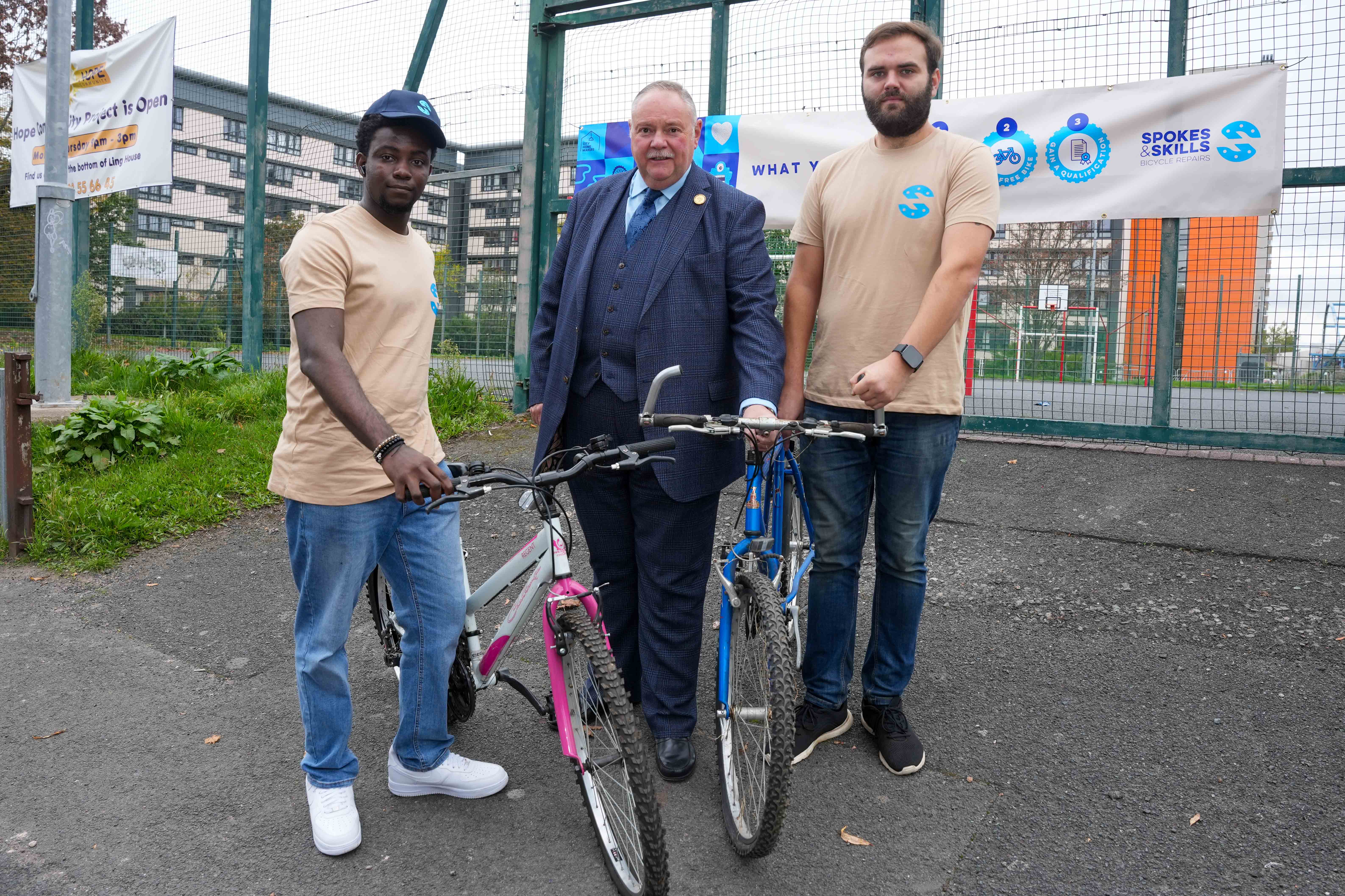Image of three men standing with bikes near a playground