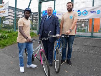 Image of three men standing with bikes near a playground