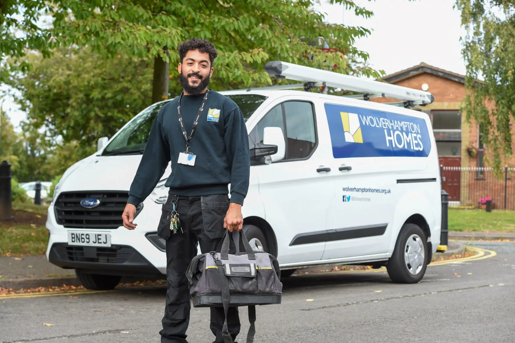 A trades operative with bag stands in front of a Wolverhampton Homes van