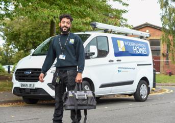A trades operative with bag stands in front of a Wolverhampton Homes van