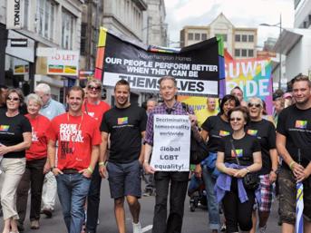 Group of people walking in a Pride parade holding a banner