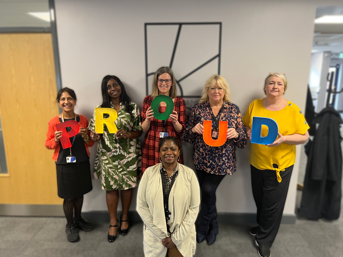 Five Wolverhampton Homes team members standing with the word 'Proud' and another sitting at the front, for Wolverhampton Pride