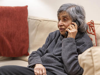 Woman wearing grey jumper, talking on the phone