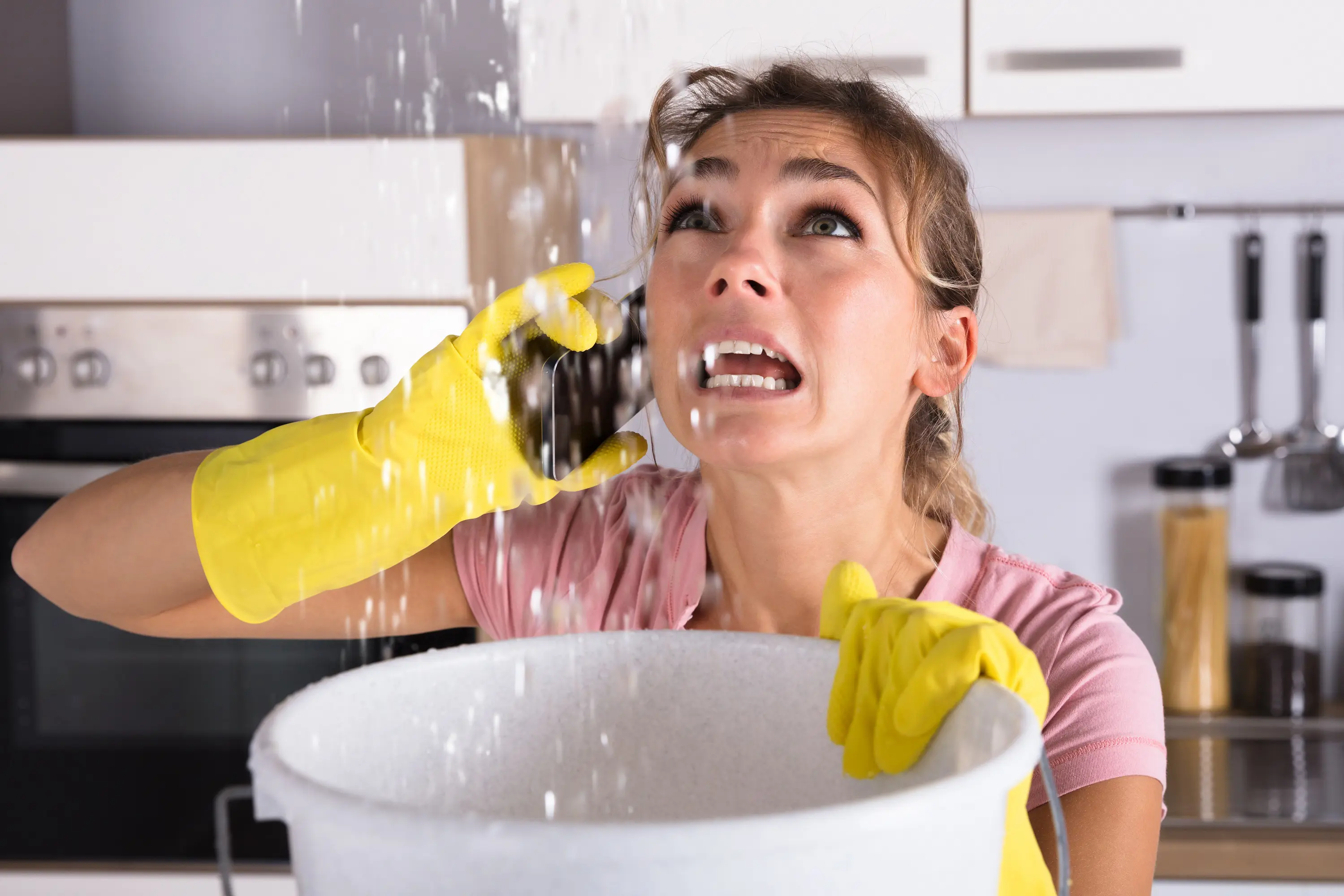 A woman with water leaking form her ceiling, on the phone