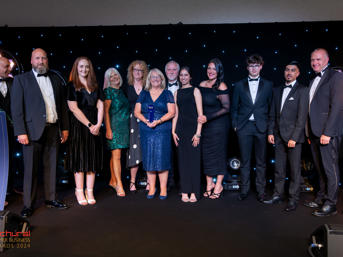 A group of WH team members in formal clothing at an awards ceremony, having won an award