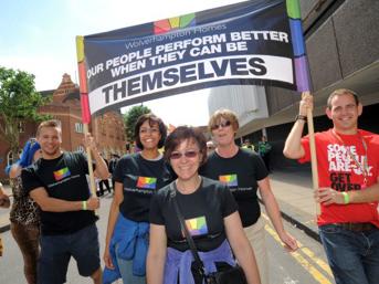Group of people walking in a Pride parade holding a banner