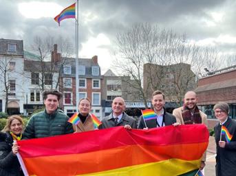 Group of people holding a rainbow flag at a Pride event