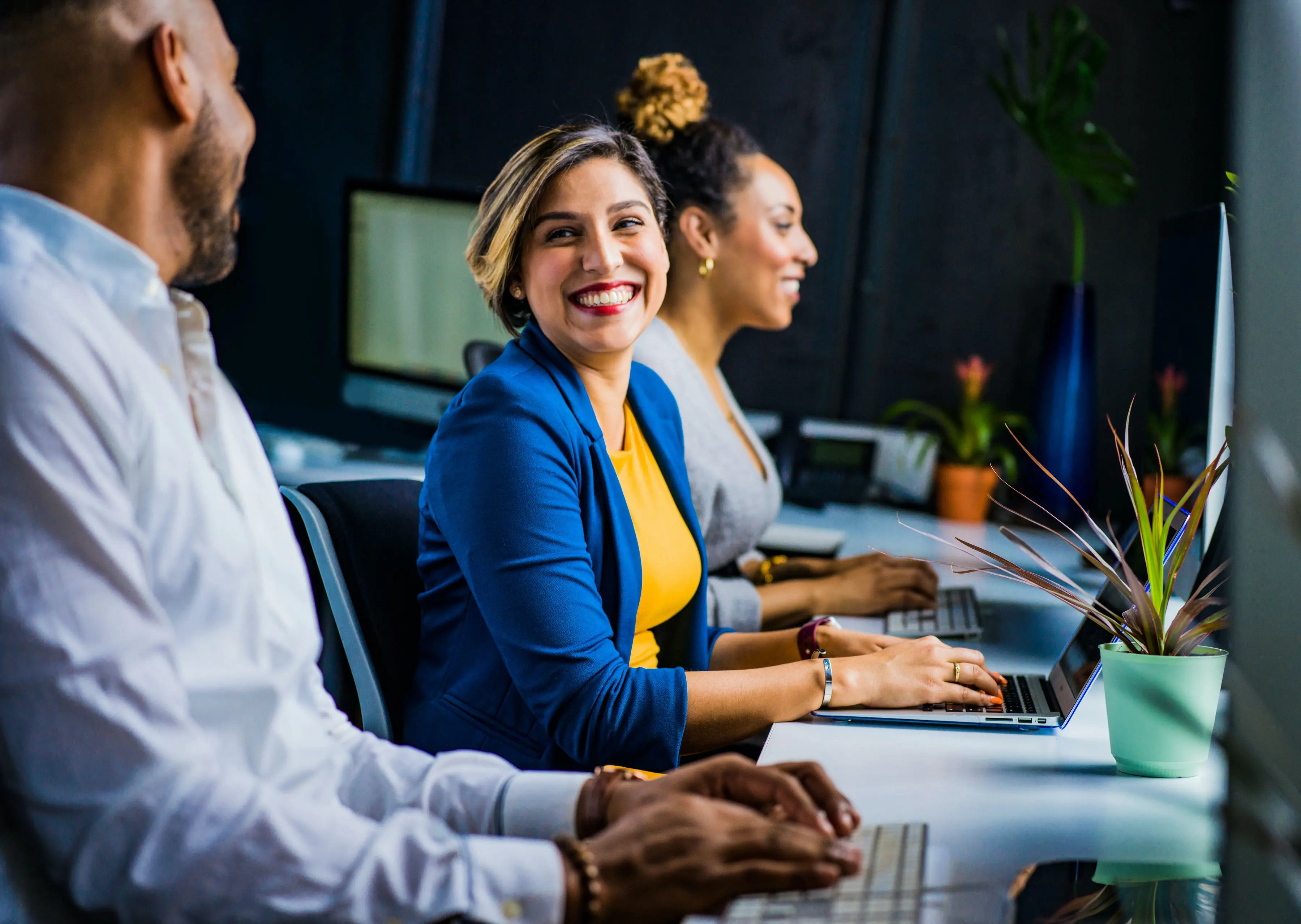 A woman at a computer smiles at a man