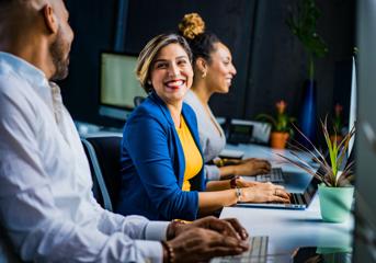 A woman at a computer smiles at a man