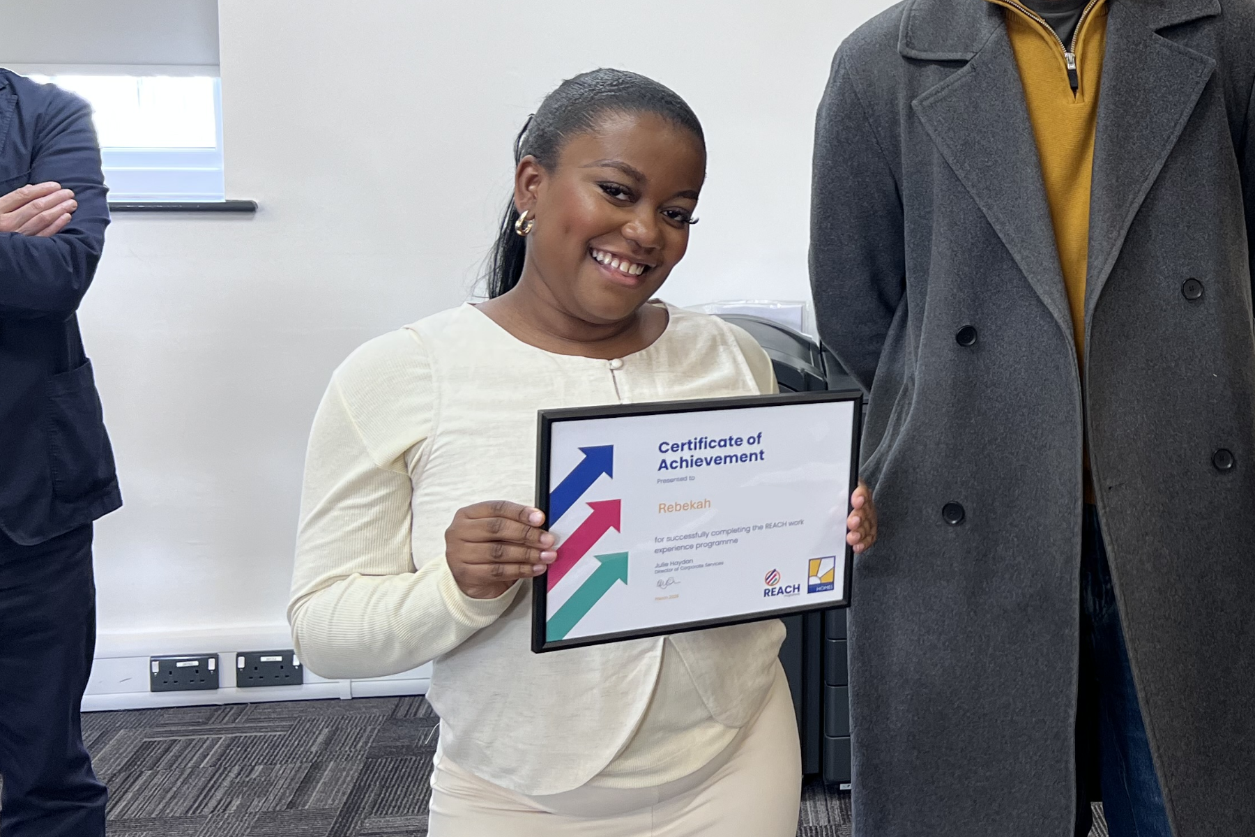 Rebekah holding a certificate of achievement and smiling at a presentation event