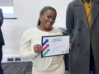 Rebekah holding a certificate of achievement and smiling at a presentation event