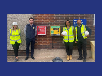 Four people stand next to a bleed kit installed outside the Wolverhampton Homes Merry Hill office