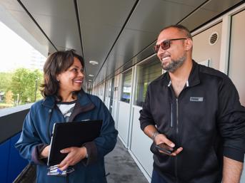 A tenant talks to a Wolverhampton Homes team member on a walkway at flats in Heath Town