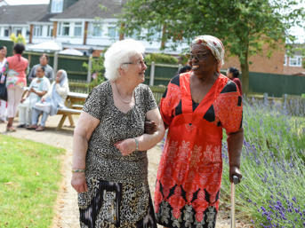 Two women, arms entwined, outside and smiling at each other