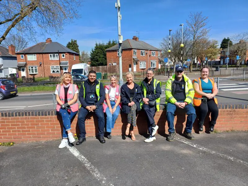 A group of seven people from Wolverhampton Homes and United Living, sitting on a wall after litter picking in Oxley