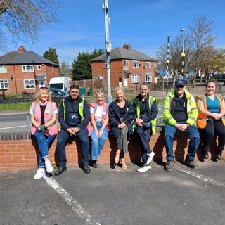 A group of seven people from Wolverhampton Homes and United Living, sitting on a wall after litter picking in Oxley