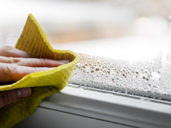 Someone wipes a window frame to remove condensation