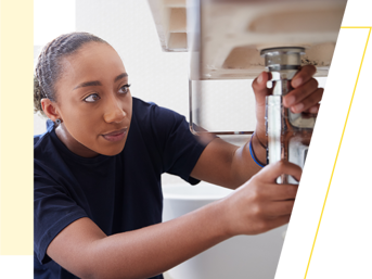 A female plumber fixes a leak on a sink
