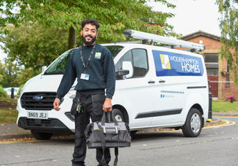 A Wolverhampton Homes operative with a bag in his hand, standing by a WH van