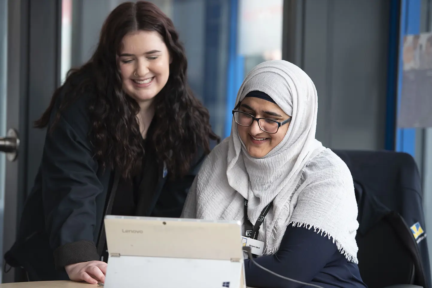 Two Wolverhampton Homes team members, one of whom is seated, look at a laptop