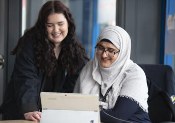 Two Wolverhampton Homes team members, one of whom is seated, look at a laptop
