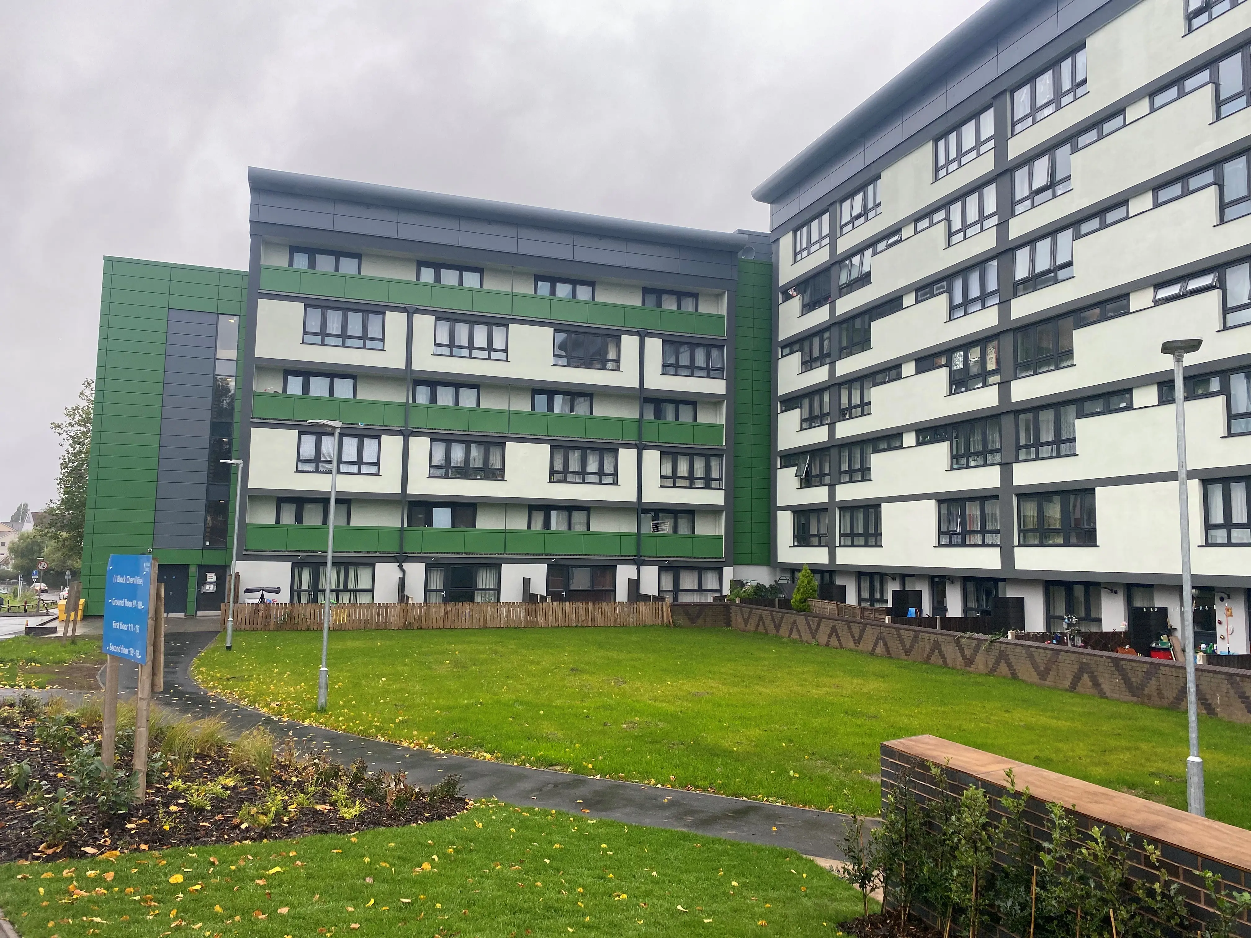 A low-rise block of flats with a green facade