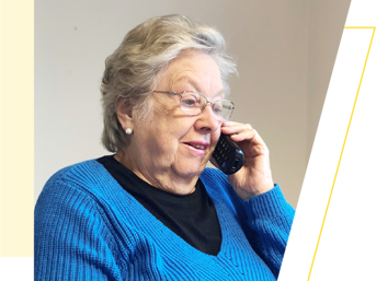 A woman in a blue jumper talks on the telephone