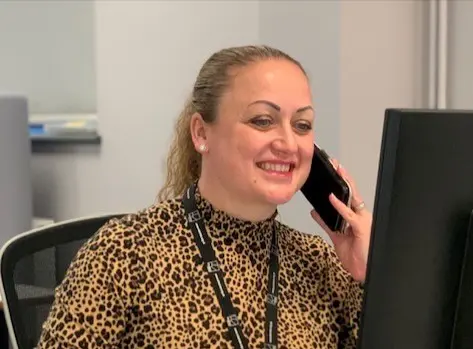 Woman on the phone smiling at a desktop computer