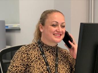 Woman on the phone smiling at a desktop computer