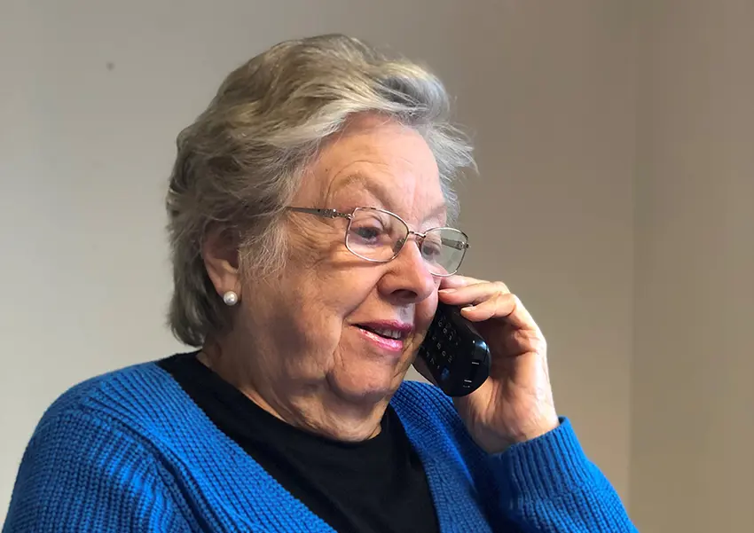 A woman in a blue jumper is speaking on a telephone