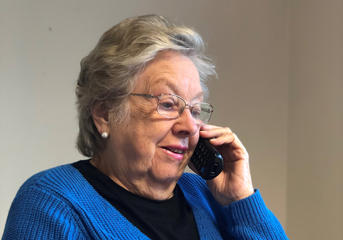 A woman in a blue jumper is speaking on a telephone
