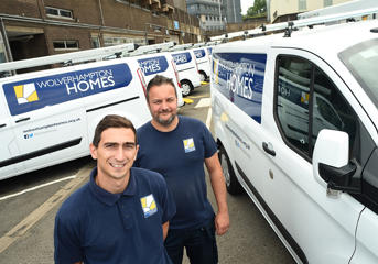 Two repairs staff standing beside Wolverhampton Homes vans