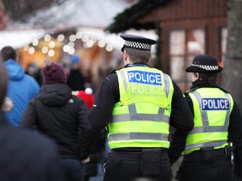 The backs of two police officers, wearing hi-vis clothing