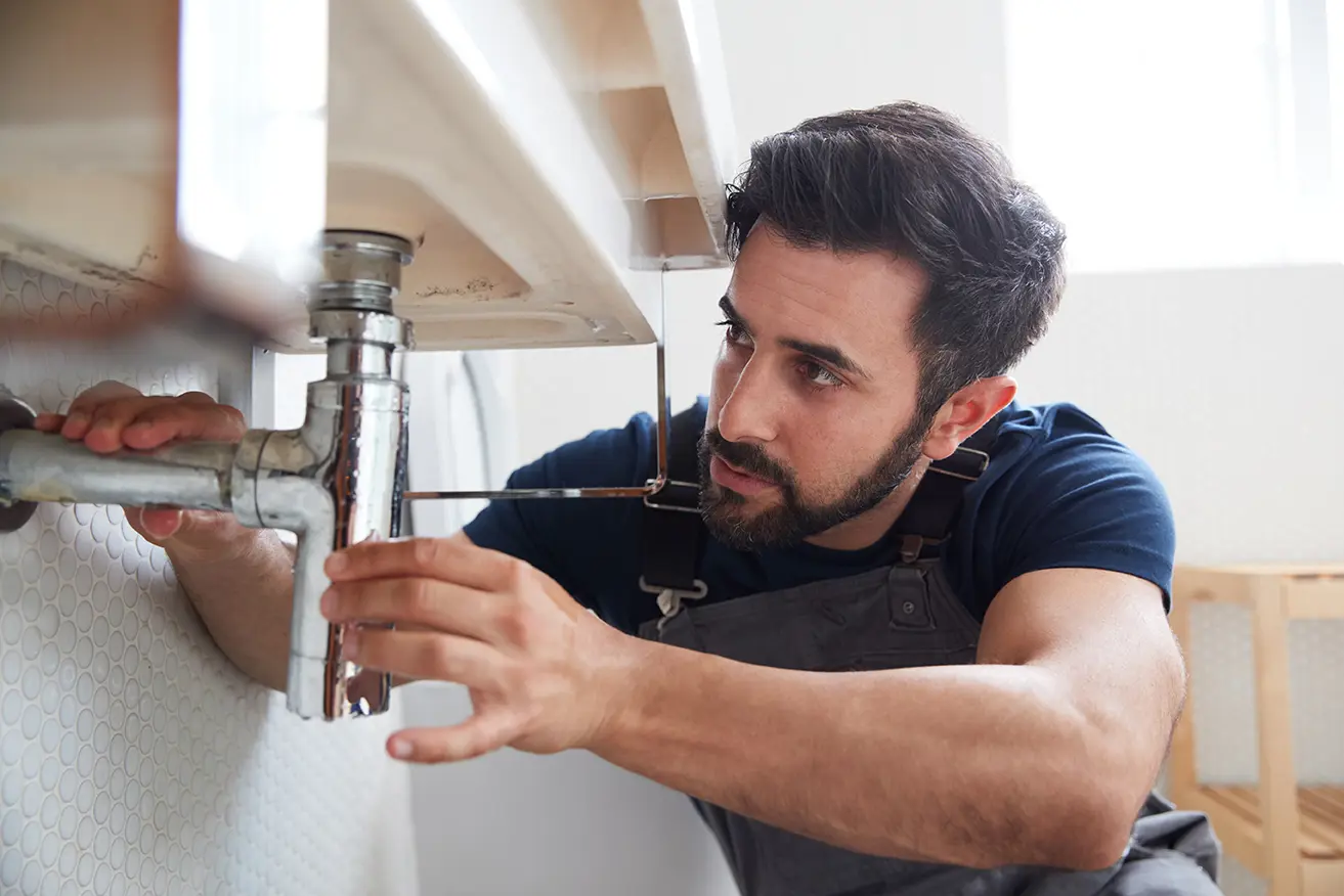 A plumber fixes a bathroom sink