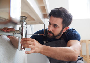 A plumber fixes a bathroom sink