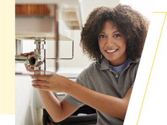 A female plumber fixes a leak on a sink