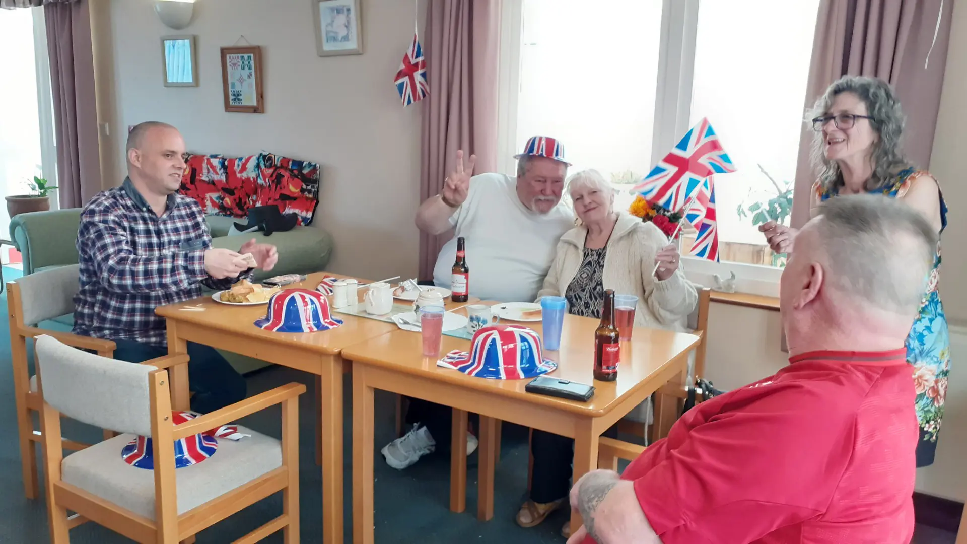 Five customers around a table, flying Union flags and wearing Union flag hats for the jubilee