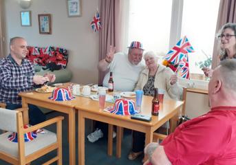 Five customers around a table, flying Union flags and wearing Union flag hats for the jubilee