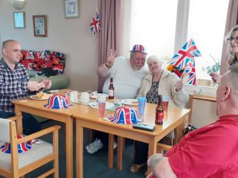 Five customers around a table, flying Union flags and wearing Union flag hats for the jubilee