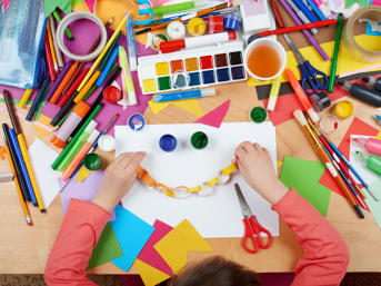 Child doing arts and crafts with paper, paint and scissors