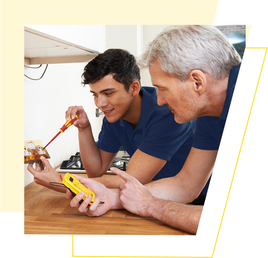 An electrician with an apprentice checks a plug socket