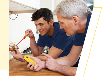 An electrician with an apprentice checks a plug socket