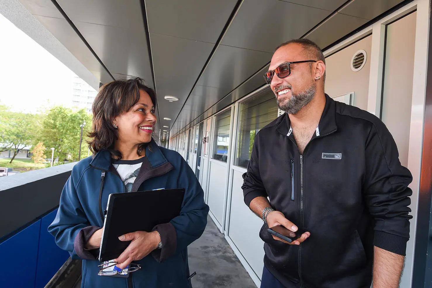 A Wolverhampton Homes team member talks to a tenant on a walkway at a block of flats