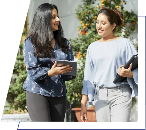 An image of two women talking to one another holding a device